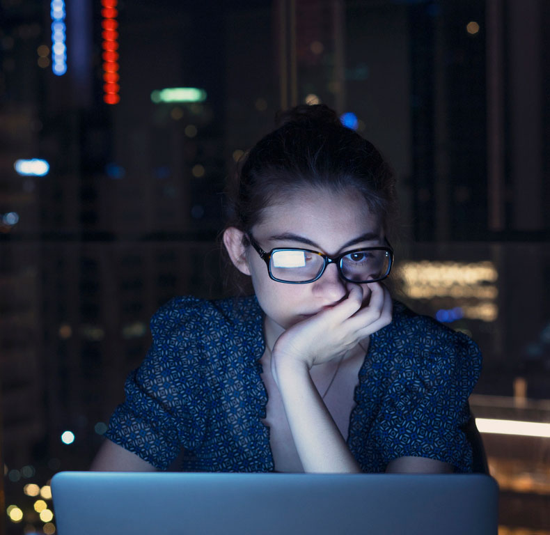 photo of a woman working on a laptop late at night